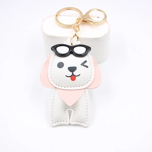 Détail d'un porte-clés chien blanc en cuir avec lunettes de soleil et fermoir doré