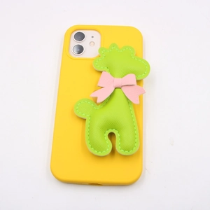 Detailed close-up of yellow phone case with green 3D giraffe pendant and pink bow