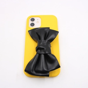 Bright yellow iPhone 11 case with a large black textured 3D faux leather bow tie