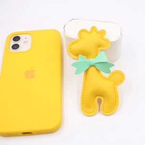 Dettaglio del ciondolo per telefono a forma di giraffa in pelle gialla con fiocco verde