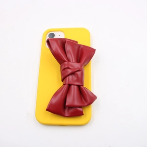 Vertical top view of yellow phone case with a large deep red leather bow accessory