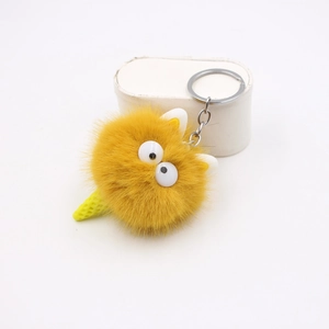 Dettaglio del portachiavi in peluche giallo con grandi occhi bianchi e catena d'argento