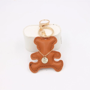 Close-up of brown leather bear keychain with golden metal clasp and rhinestone detail