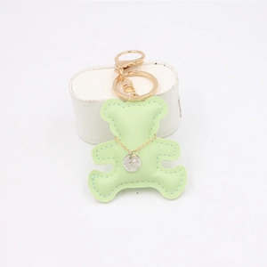 Detail of mint green leather bear keychain with gold hardware and engraved silver tag