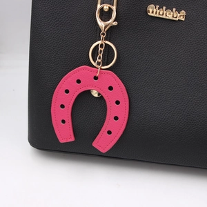 Macro detail of horseshoe PU leather bag charm in rose pink with gold metal clasp