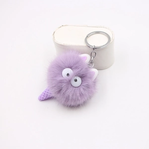 Dettaglio macro di un ciondolo mostro di peluche viola con pelliccia e portachiavi