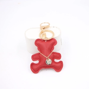 Detailed close-up of red leather bear keychain with premium golden metal hardware