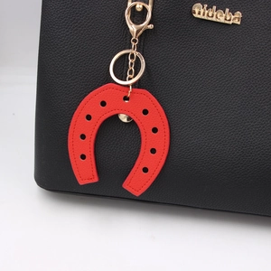 Red horseshoe PU leather bag charm and keychain with golden metal clasp on black bag