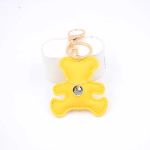 Detail of yellow leather bear keychain with gold chain, crystal charm and fine stitching