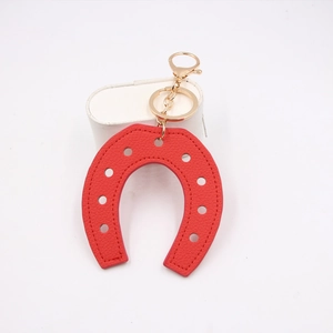 Close-up of red horseshoe leather bag charm with gold metal clasp and key ring