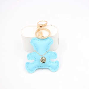 Close-up of light blue leather bear keychain with golden charm and detailed stitching