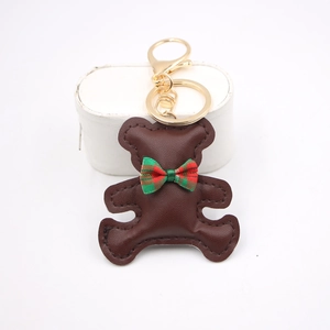 Close-up of brown leather bear keychain with red green plaid bow and golden metal ring