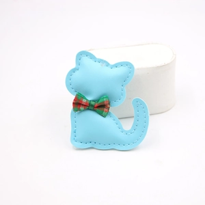 Detalle de colgante de cuero azul cielo con forma de gato y lazo de cuadros escoceses
