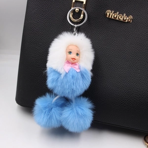Close-up of a blue and white plush doll keychain hanging on a black leather handbag