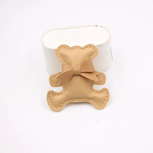 Detailed view of camel leather bear charm with stitched edges and bow accent