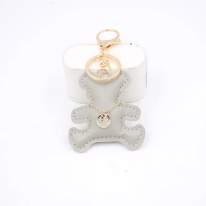 Gray leather bear keychain charm with gold decorative chain and sparkling pendant on stand