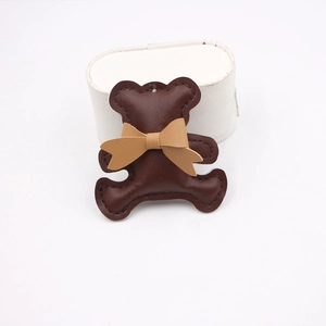 Detail of a brown leather bear charm featuring fine stitching and a cute bow accessory
