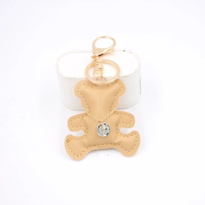 Detailed view of a khaki leather bear keychain with gold clasp and chain necklace decor