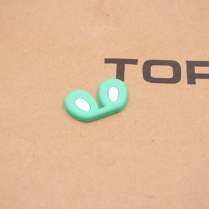 Close-up of mint green silicone rabbit ear shoe charms with white inner detail