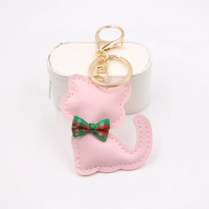 Dettaglio di un portachiavi a forma di gatto in pelle rosa con fiocco a quadri e gancio d'oro