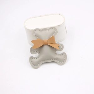 Detail of a handmade grey leather bear charm with a brown bow and white stitching
