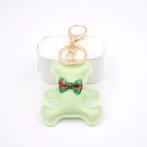 Detail of light green faux leather bear keychain with tartan bow and golden lobster clasp
