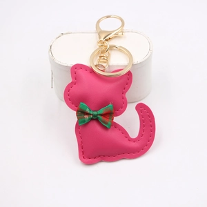 Dettaglio portachiavi gatto in pelle rosso rosa con fiocco a quadri e chiusura dorata
