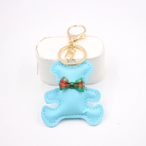 Close-up of light blue leather teddy bear keychain with British plaid bow and gold metal clasp