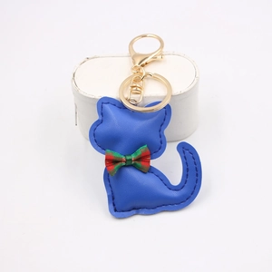 Dettaglio di un portachiavi a gatto in pelle blu con fiocco a quadri e gancio dorato