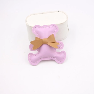 Detail of pink leather bear charm with brown bow and white stitching for DIY crafts