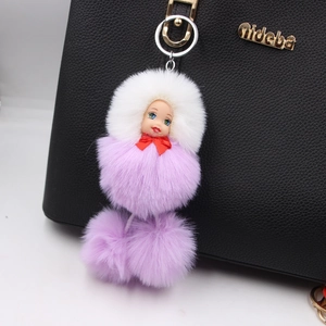 Cute sleeping doll keychain with purple and white faux fur pompom on a black leather bag