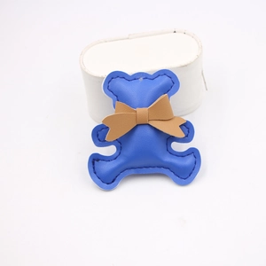 Detailed close-up of a blue faux leather bear charm with fine stitching and a brown bow