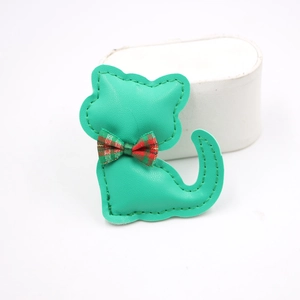 Detalle del colgante de gato en cuero verde con lazo de cuadros rojos y verdes y costuras