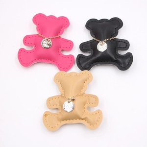 Close-up of three colorful PU leather bear charms in magenta, black, and light brown