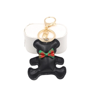 Cute black leather bear keychain with a plaid bowtie and golden lobster clasp on display