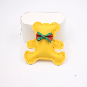 Detail of yellow leather bear charm with red and green plaid bowknot for phone cases