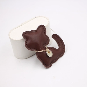 Dark brown leather cat-shaped pendant with a gold chain and metal tag for accessories