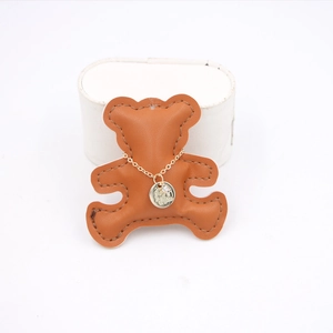 Close-up of gold coin relief necklace with crystal inlay on a brown bear leather pad
