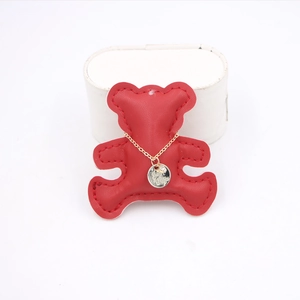 Detail shot of a golden necklace with engraved round pendant on a red bear leather mount
