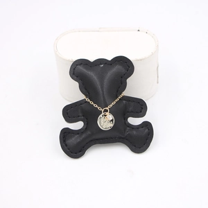 Gold chain necklace with engraved zircon round pendant on black bear display stand