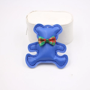 Detailed close-up of blue leather bear phone strap with a red and green plaid bow tie