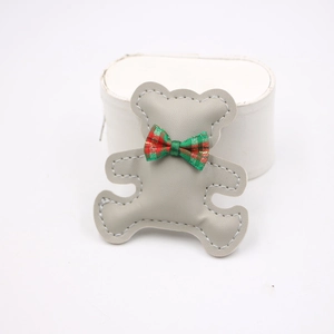 Detail of grey PU leather bear accessory with plaid bowtie and white stitching