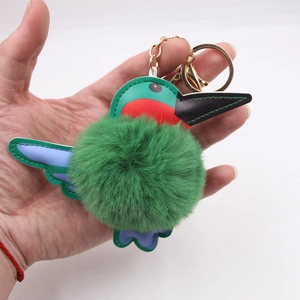Green hummingbird plush keychain accessory with colorful faux leather wings and gold clasp