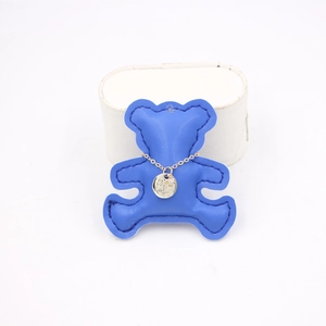 Detail of a gold disc pendant with fine engraving on a navy blue leather bear stand