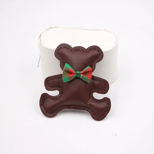 Detail of a dark brown PU leather bear accessory with a red and green plaid bow tie