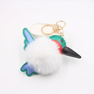 Close-up of hummingbird plush keychain showing green leather wings and gold hardware