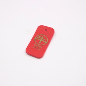 Detail of red faux leather tag with golden Good Luck text and ox character print