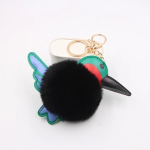 Detail of plush hummingbird keychain with green and blue faux leather wings and gold clasp