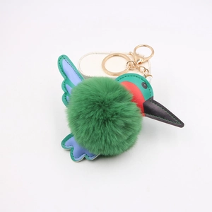 Close-up of plush kingfisher keychain with green pom-pom and gold metal clasp