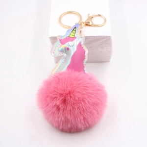 Detail of pink faux fur pompom keychain with holographic laser unicorn charm and gold ring